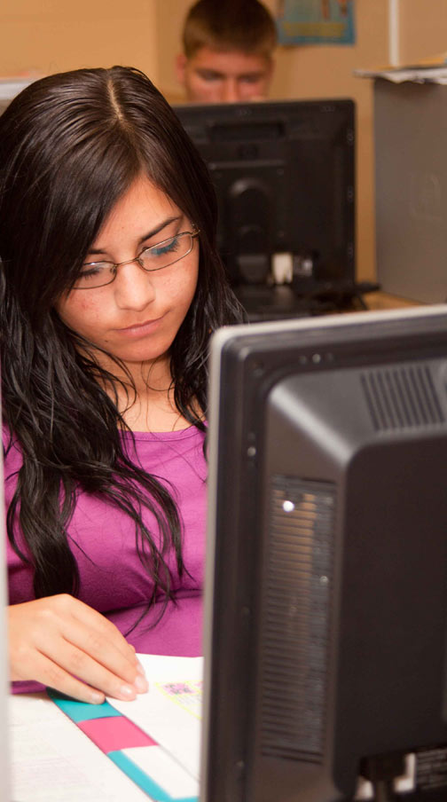 A female student working at her computer in a classroom; Shutterstock.com